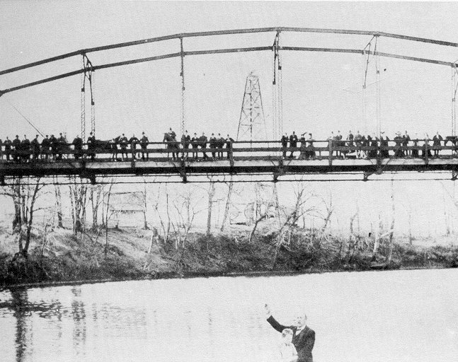 The gathering at the river.  A baptism occurs near the first road bridge across the Caney River at Bartlesville, Indian Territory, 1905.  (Elmer Sark Collection, Bartlesville Public Library)